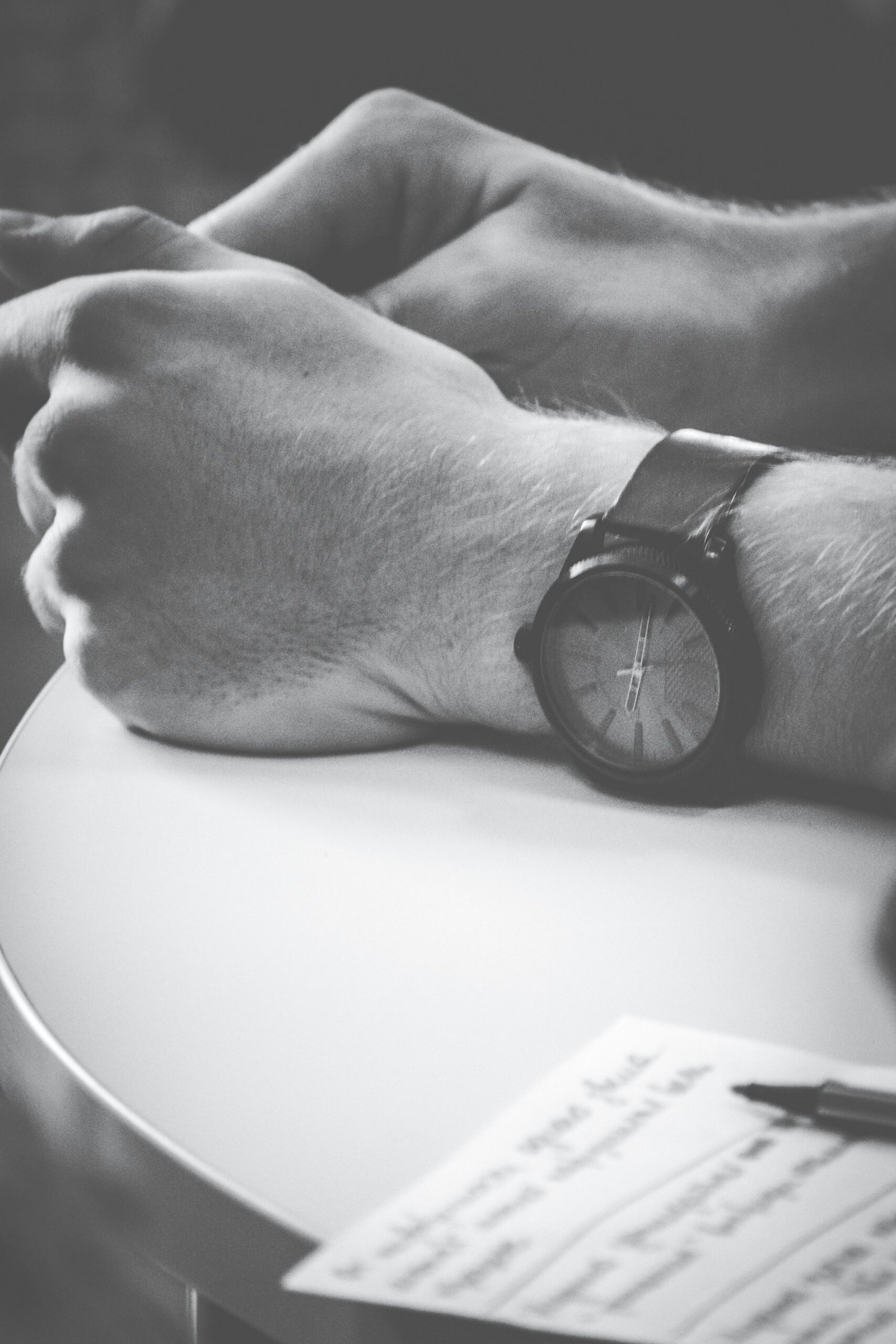 person wearing black watch with hand on table